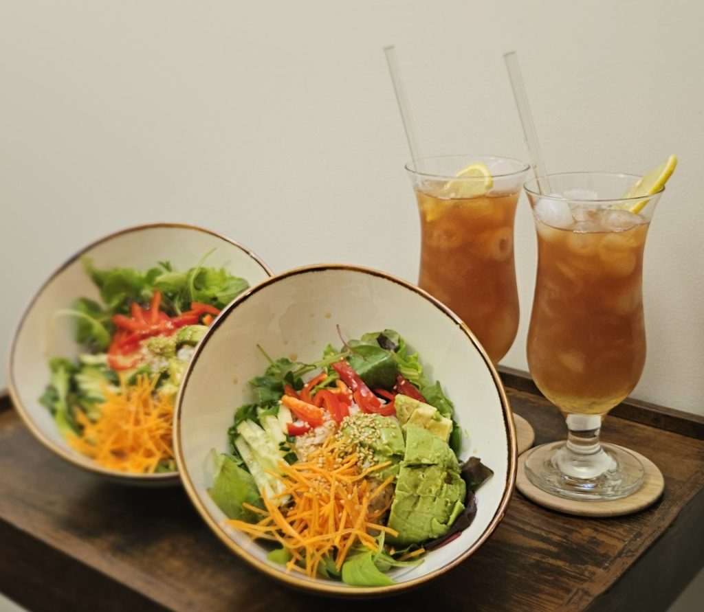 Zwei Schalen Salat und Getränke auf einem Tablett.